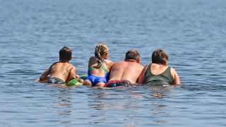 ARCHIV - 19.07.2022, Brandenburg, Storkow: Eine Familie schwimmt auf einer Luftmatratze im Wasser eines Sees. (Quelle: dpa/Patrick Pleul)