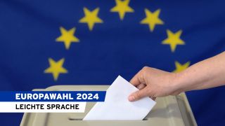 Symbolbild:Eine Hand steckt einen Umschlag in eine Wahlurne vor der Europafahne.(Quelle:picture alliance/ZB/P.Endig)