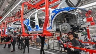Symbolbild: Mitarbeiter der Tesla Gigafactory Berlin Brandenburg arbeiten an einer Fertigungslinie eines Elektrofahrzeuges. (Quelle: dpa/Pleul)