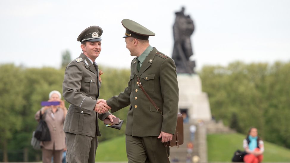 Ein Besucher in NVA-Uniform (l) und ein anderer Besucher in sowjetischer Uniform begrüßen sich am 08.05.2015 in Berlin am Sowjetischen Ehrenmal in Treptow. (Quelle: dpa)