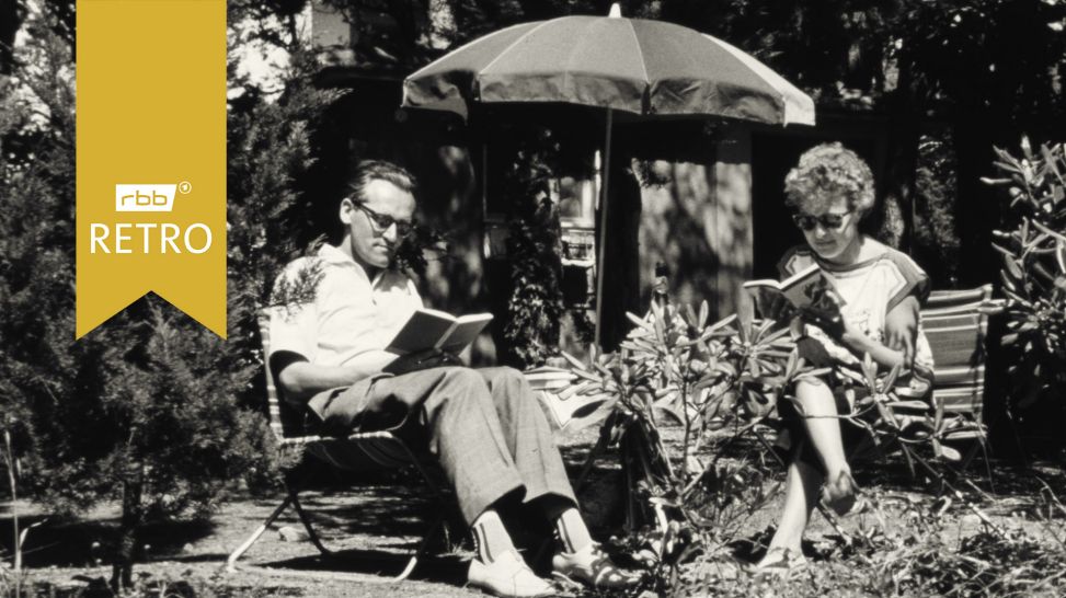 Schwarz-Weiß-Foto: Ein Mann und eine Frau sitzen unter einem Sonnenschirm in einem Garten und lesen; Logo "rbb Retro"(Quelle: rbb/imago images/serienlicht)