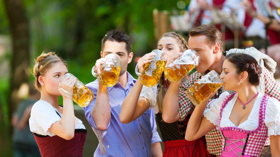 Drei Frauen und zwei Männer in Trachten trinken Bier im Biergarten (Bild: Colourbox)