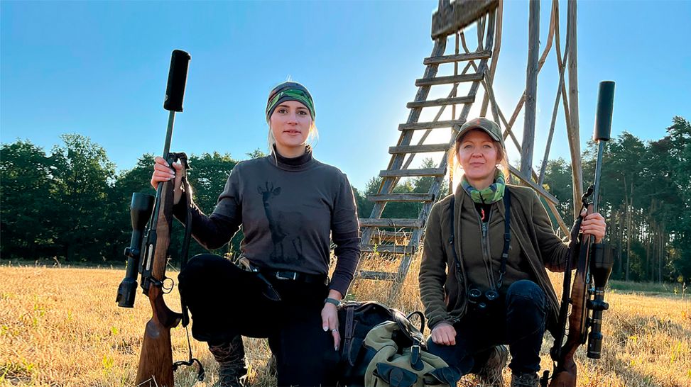 Jägerinnen in der Lausitz knien mit Gewehr auf einem Feld vor einem Hochsitz (Bild: rbb/Konstanze Schirmer)