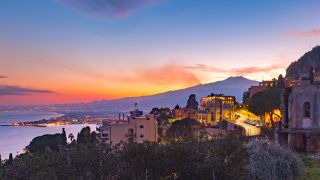 Panoramablick auf Taormina auf der Insel Sizilien mit dem Vulkan Ätna bei Sonnenuntergang im Hintergrund (Bild: Colourbox)
