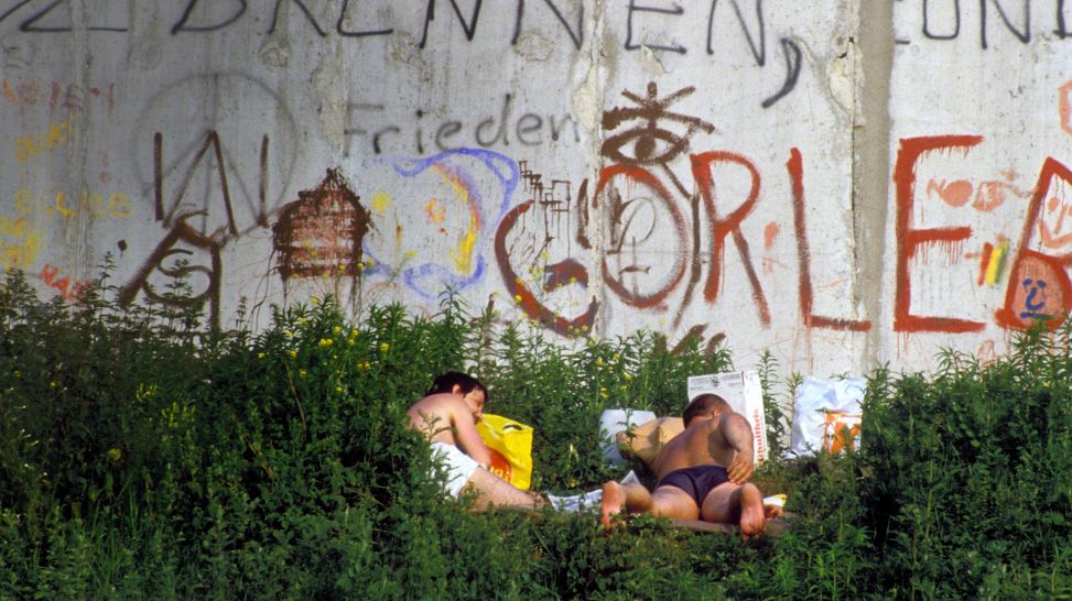 Männliche Sonnenanbeter an der Berliner Mauer im Bezirk Kreuzberg am 01.07.1986 (IMAGO / Sven Simon)