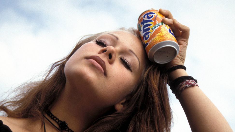 Junge Frau kühlt sich die Stirn mit kalter Getränkedose (Quelle: imago/Steinach)
