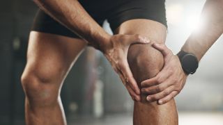 Kreuzbandriss: Bild zeigt Sportler, der sich schmerzendes Knie hält (Bild: imago images/Zoonar ll)