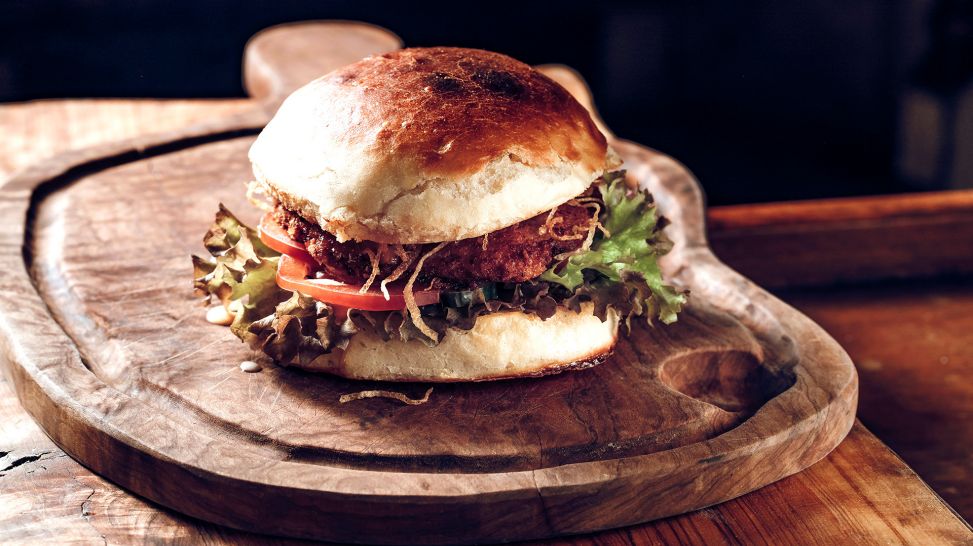 Fett in der Ernährung: Hamburger liegt auf einem Holzbrett (Bild: colourbox.de/Dmitriy Spynda)