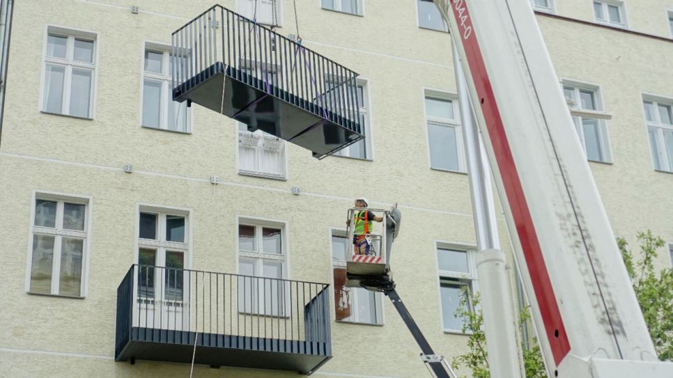 Balkone werden an einem Berliner Mehrfamilienhaus befestigt (Quelle: imago images / viennaslide)