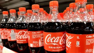 Coca Cola-Flasche in einem Supermarkt-Regal (Quelle: IMAGO / Martin Wagner)