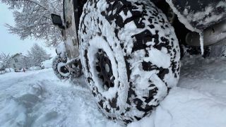 Ein zugeschneiter Reifen an einem Auto (Quelle: imago images/Sven Simon)