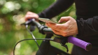 Ein Mann macht eine Fahrradtour und checkt zwischendurch sein Smartphone (Quelle: imago images/Pond5 Images)