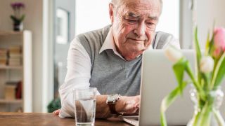 Ein älterer Mann schaut sorgenvoll auf den Laptop (Quelle: IMAGO / Westend61)