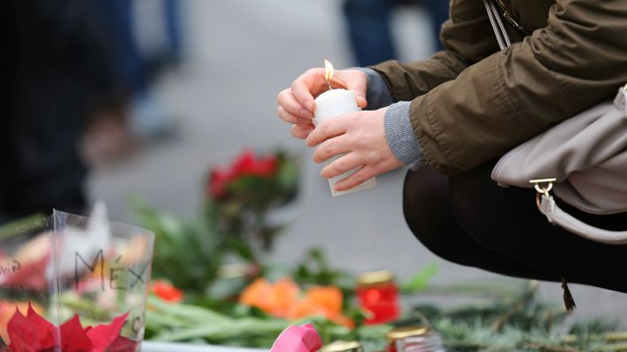 Eine Trauernde zündet eine Kerze für die Opfer des Weihnachtsmarkts am Breitscheidplatz an. (Quelle: imago | Simone Kuhlmey)