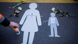 Symbolbild: Weiße Silhouetten einer Frau und eines Kindes liegen neben Blumen und Kerzen bei einer Mahnwache auf der Leipziger Straße. (Quelle: dpa/Soeder)