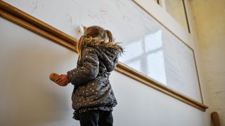 Symbolbild:Ein geflüchtetes Kind schreibt etwas an das Whiteboard im Klassenzimmer.(Quelle:imago images/R.Klar)