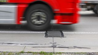 Symbolfoto: Ein Lkw fährt über eine notdürftig geflickte Schadstelle von Betonkrebs (Quelle: dpa/Jan Woitas).
