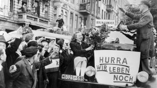Unter dem Jubel von Bürgern verlassen am frühen Morgen des 12.05.1949 die ersten Busse Berlin in Richtung Westdeutschland. Ein Personenbus ist mit einem Schild dekoriert auf dem "Hurra wir leben noch" steht. In der Nacht vom 11. zum 12. Mai 1949 wurde um 0.01 Uhr die Blockade Berlins aufgehoben (Quelle: dpa / UPI).
