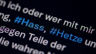 Auf dem Bildschirm eines Smartphones sieht man die Hashtags (#) Hass und Hetze in einem Twitter-Post. (Quelle: dpa/Fabian Sommer)