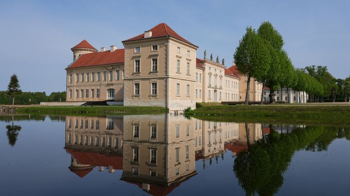 Archivbild: Die Parkseite von Schloss Rheinsberg mit dem Kurt Tucholsky Literaturmuseum spiegelt sich in dem vom Grienericksee gespeisten Wasser des Schlossgrabens. (Quelle: dpa/Stache)