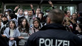Teilnehmer einer Pro-Palästinenser-Demonstration der Gruppe "Student Coalition Berlin" im Theaterhof der Freien Universität Berlin, davor steht ein Polizist (Quelle: dpa/Markus Schreiber)