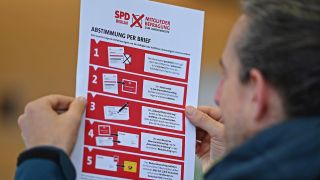 Symbolbild:Ein Mann hält bei der Übergabe der Wahlbriefe zur SPD-Mitgliederbefragung an die Deutsche Post das Merkblatt zur Briefwahl in der Hand .(Quelle:picture alliance/dpa/B.Pedersen)