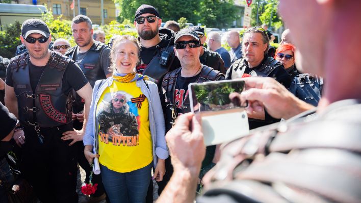 Eine Frau mit einem T-Shirt, auf dem der russische Präsident Putin zu sehen ist, posiert mit Mitgliedern der russisch-nationalistischen Rockergruppe "Nachtwölfe" außerhalb des Sowjetischen Ehrenmals am Treptower Park.