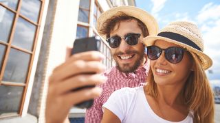 Ein Pärchen mit Sommerhüten und Sonnenbrillen machen ein Selfie von sich (Foto: www.colourbox.de)