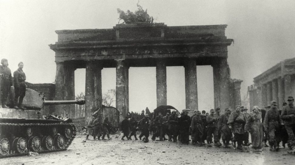 Soldaten der Wehrmacht nach der Kapitulation auf dem Weg in die Kriegsgefangenschaft passieren 1945 das Brandenburger Tor in Berlin (Bild: dpa)