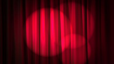 Ein roter Theatervorhang mit Scheinwerferlicht drauf (Bild: Colourbox)
