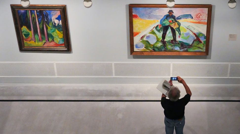 Ein Mann fotografiert mit seinem Smartphone in der Berlinischen Galerie während der Pressevorbesichtigung zur Ausstellung "Edvard Munch. Zauber des Nordens" das Bild "Der Mann im Kohlacker" (Bild: dpa / Soeren Stache)