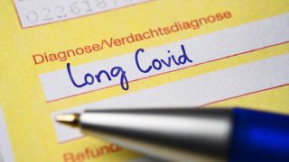 Auf einem Ã¤rztlichen Ãberweisungsschein liegt ein blauer Kugelschreiber, mit dem zuvor die Diagnose Long Covid geschrieben worden ist.