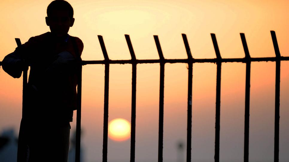 Ein Jugendlicher steht in einem Flüchtlingslager in Libyen an einem Zaun (Bild: dpa)