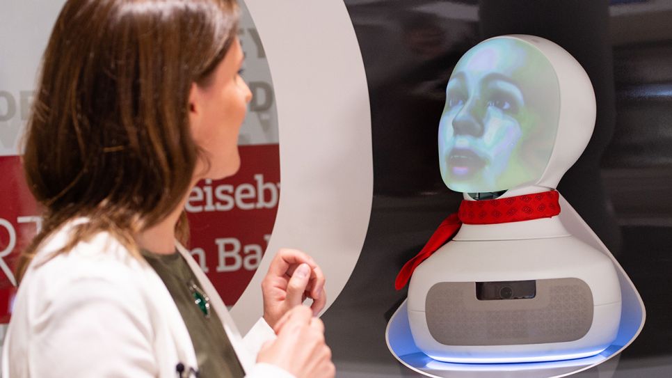 Eine Frau spricht mit einem Roboter vom Kundenservice der Deutschen Bahn, 2019; © dpa/Lisa Ducret