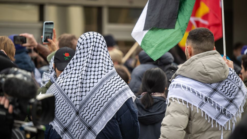 Teilnehmer der propalästinensischen Kundgebung unter dem Motto „Solidarität mit Palästina“ stehen mit Palästinenser-Tüchern und Flaggen vor der Mensa II an der Freien Universität Berlin, 08.02.2024; © dpa/Monika Skolimowska