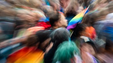 Ein Mann, der an der Christopher-Street-Day-Parade in der Innenstadt teilnimmt, hält eine Regenbogen-Fahne © picture alliance/dpa/Peter Kneffel