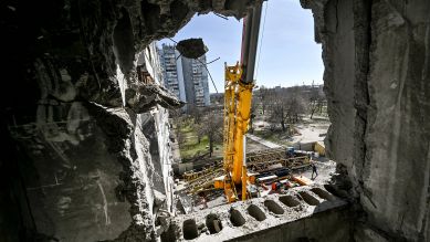 Ein Kran steht vor einem zerstörten Gebäude in Zaporizhzhia, Foto: IMAGO/Dmytro Smolienko