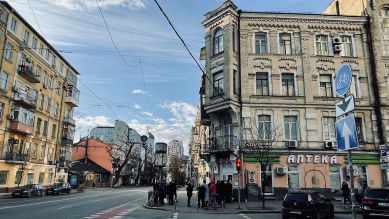 Blick auf de eine Straße in Kiew am 26.02., Menschen stehen vor einer Apotheke Schlange © Yevgenia Belorusets