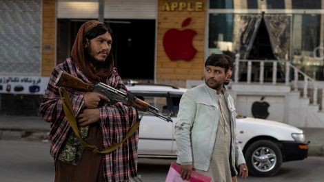 Ein Afghane schaut an einem Checkpoint auf einen Taliban-Kämpfer, November 2021; dpa/Petros Giannakouris