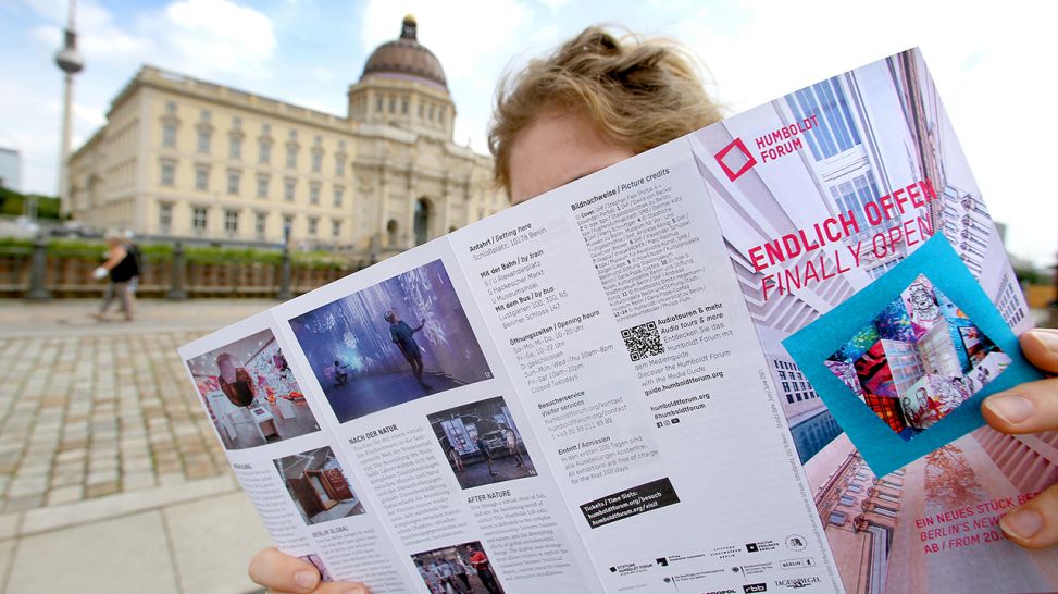 Eine junge Frau studiert vor dem Humboldt Forum eine Broschüre © dpa/Wolfgang Kumm