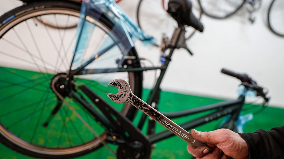 "Im Fahrradladen hält ein Mechaniker einen Schraubenschlüssel in der Hand."; © dpa/ Gerald Matzka