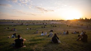 Menschen sitzen auf dem Tempelhofer Feld. Bild: Sebastian Gollnow/dpa