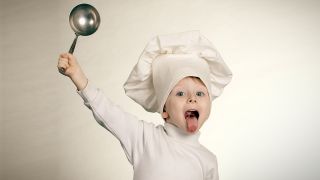 Ein Kind schwingt einen Kochlöffel und hat eine Kochmütze auf dem Kopf (Quelle: Colourbox)