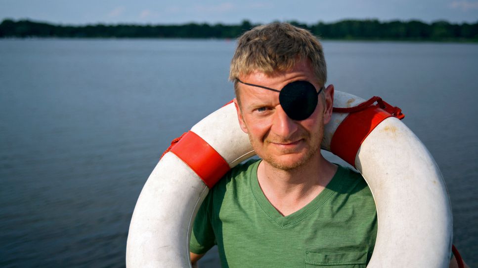 Michael Kessler mit Augenklappe und Rettungsreifen (Bild: rbb/Stefan Wieduwilt)