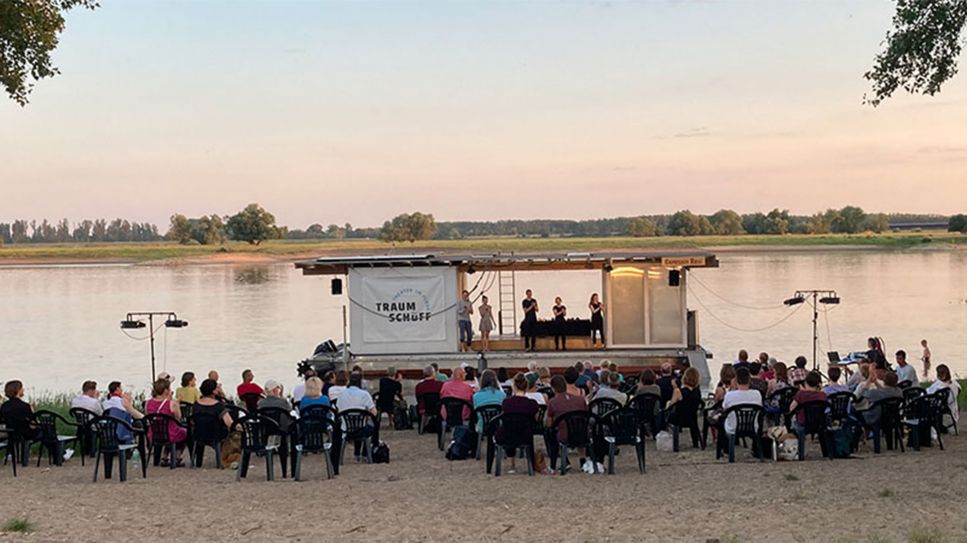 Sitzende Gäste vor dem Traumschüff - Theater im Fluss (Quelle: rbb/RosaToplak)