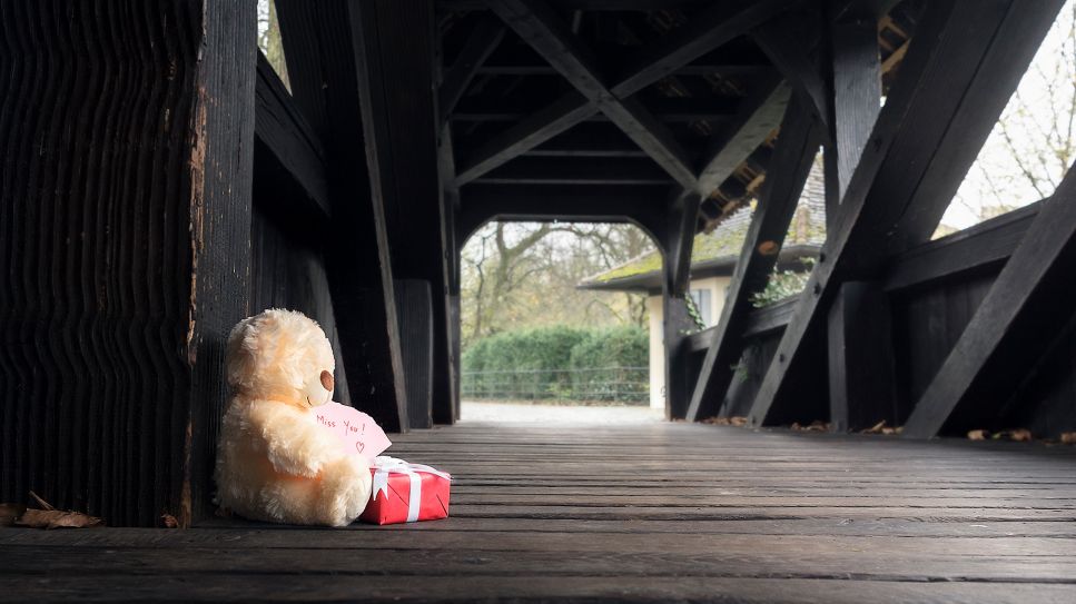 Kuscheltier (Teddy) mit Geschenk und Zettel "Miss you" auf leerer Holzbrücke (Bild: Colourbox/Daniela Simona Temneanu)