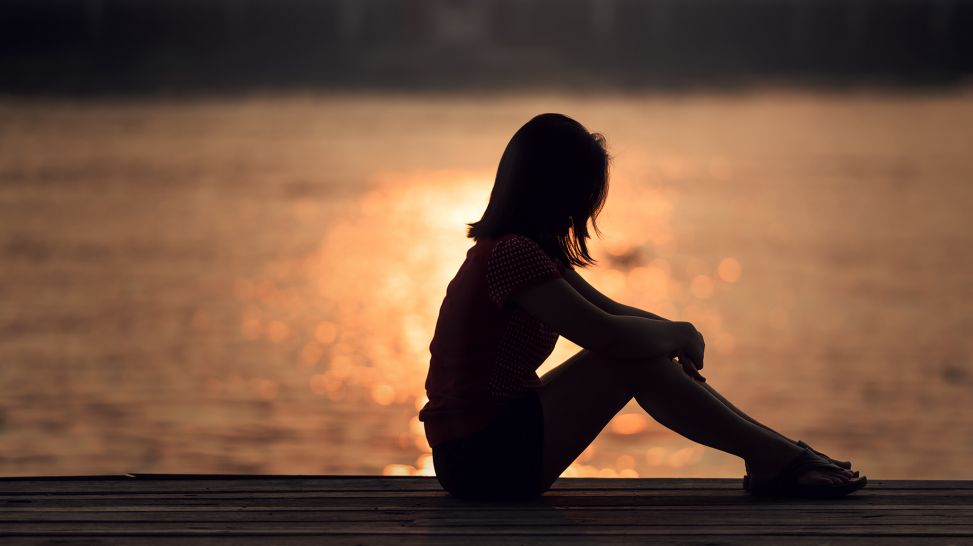 Frau sitzt bei Sonnenuntergang am Wasser (Bild: Colourbox/Sasin TIPCHAI)