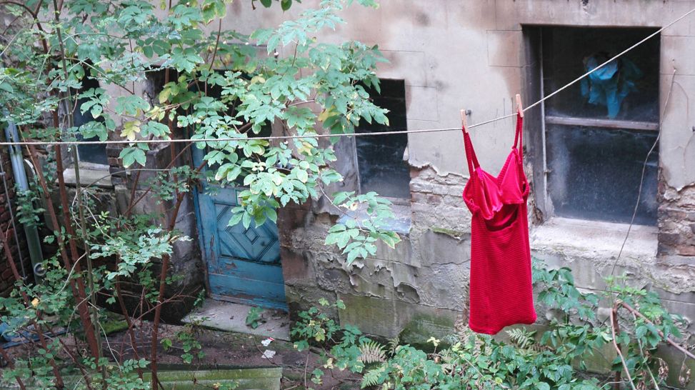 Rotes Kleid an einer Leine im Innenhof des Stadtbades in der Oderberger Straße in Berlin - Prenzlauer Berg, Bild: IMAGO / Steinach