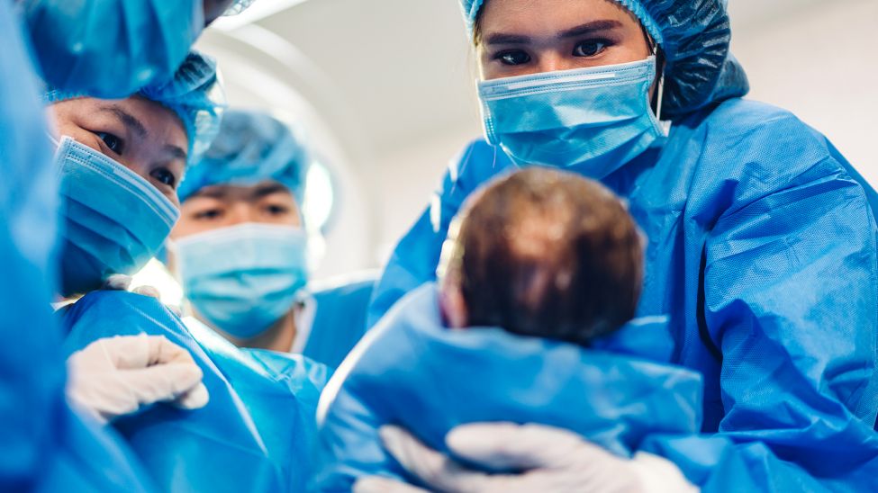 Ärzteteam mit neugeborenem Baby (Bild: Colourbx)