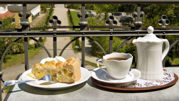 Kaffeetasse und Kännchen mit Kuchen, Ausblick in Garten (Quelle: imago/imagebroker/siepmann)